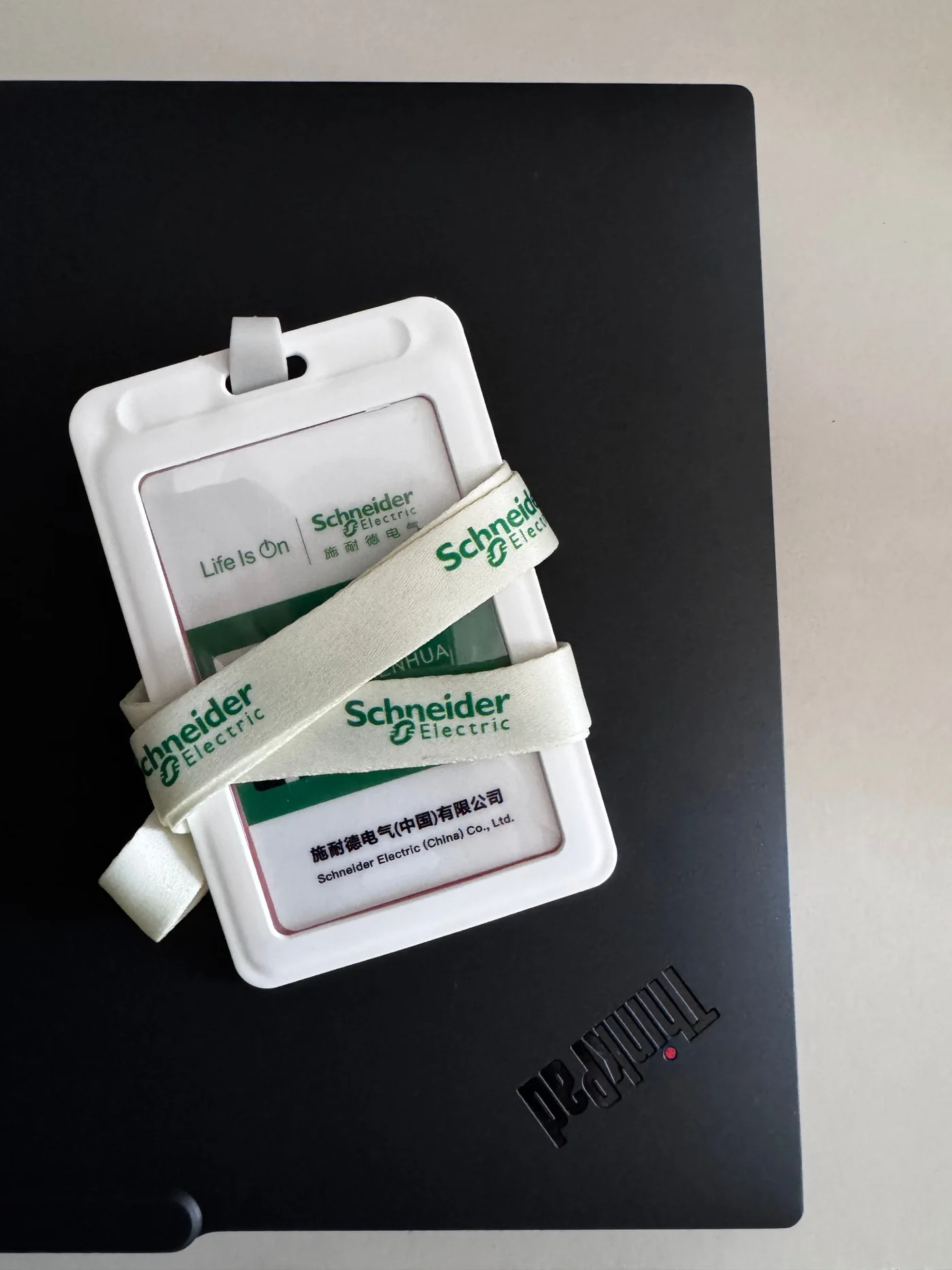 Schneider Electric employee badge and lanyard resting on a ThinkPad, documenting Zhenhua Chen's professional experience.